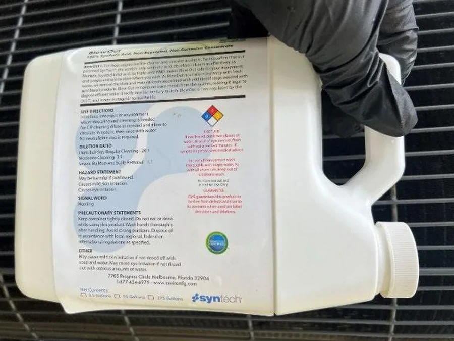 Non-corrosive coil descaler dosed at a condenser during in-place service